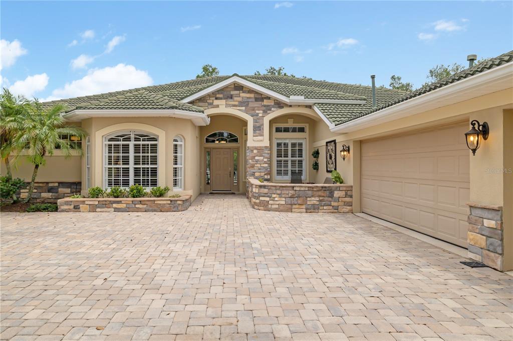 A screened-in swimming pool with a water feature and patio area behind a two-story house — 12471 NATUREVIEW CIRCLE, BRADENTON, FL