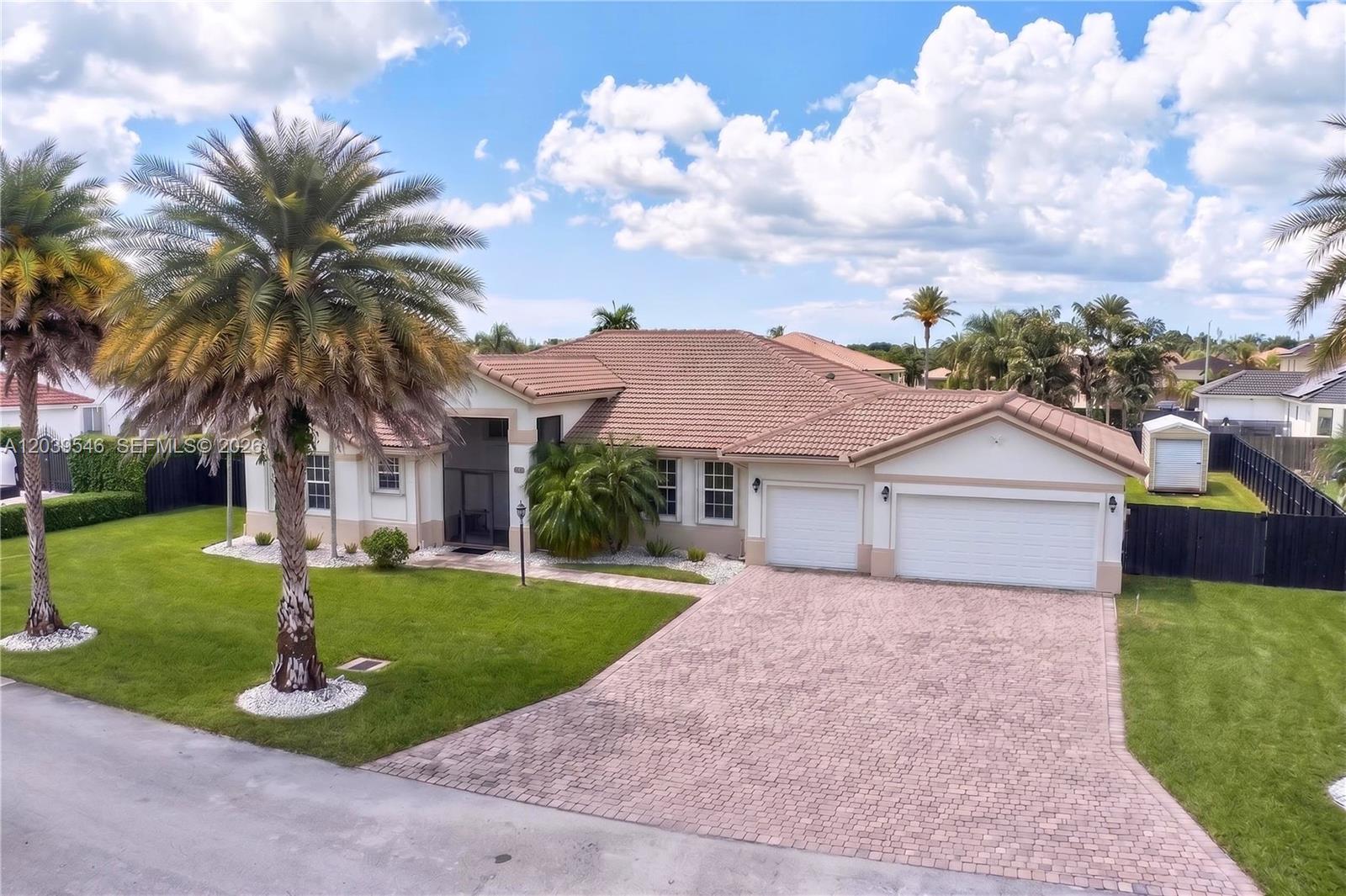 An aerial view of a single-story house with a tiled roof, palm trees, and driveway — 12922 SW 221 St, Miami FL 33170, MIAMI, FL