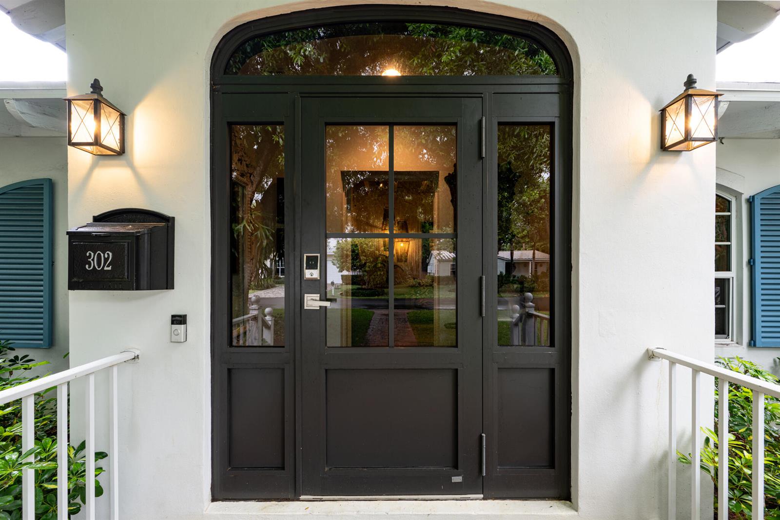 A dark-framed glass front door with sidelights and an arched transom window on a white house — 302 NW 16th Street, Delray Beach FL 33444, DELRAY BEACH, FL