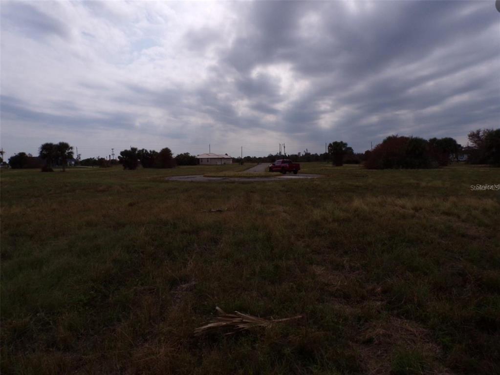A red pickup truck is parked on a circular driveway in a large, grassy field — 18 GULL COURT, PLACIDA, FL