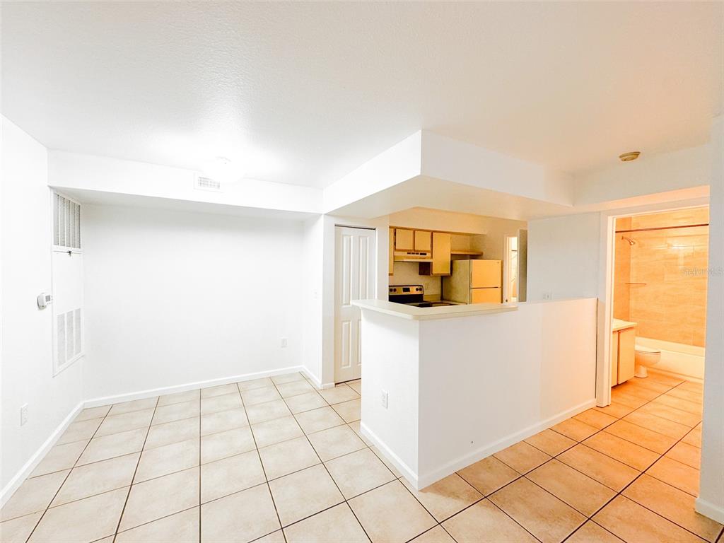 A tiled dining area opens to a kitchen with light cabinets and an adjacent bathroom — 3032 PARKWAY BOULEVARD UNIT 101, KISSIMMEE, FL