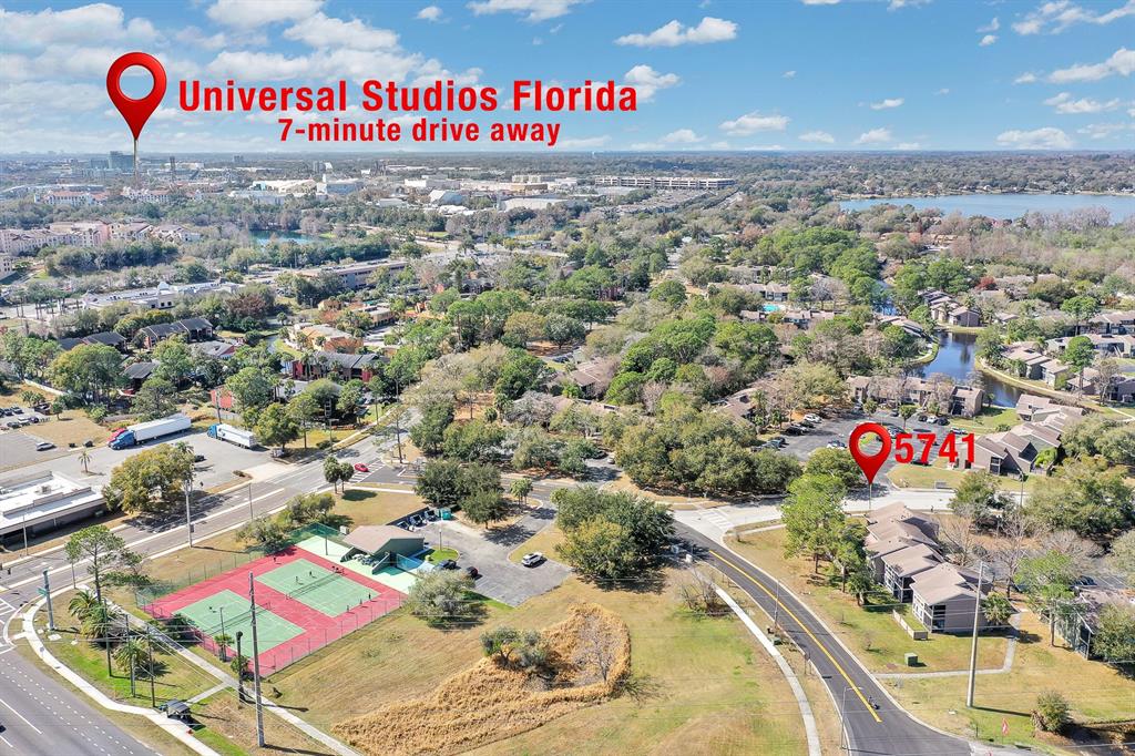 This aerial view shows a residential complex with tennis courts and surrounding trees — 5741 PEREGRINE AVENUE UNIT 28A, ORLANDO, FL