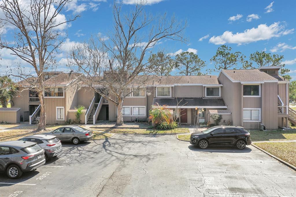 A two-story apartment building with brown siding and a parking lot in the foreground — 5741 PEREGRINE AVENUE UNIT 28A, ORLANDO, FL