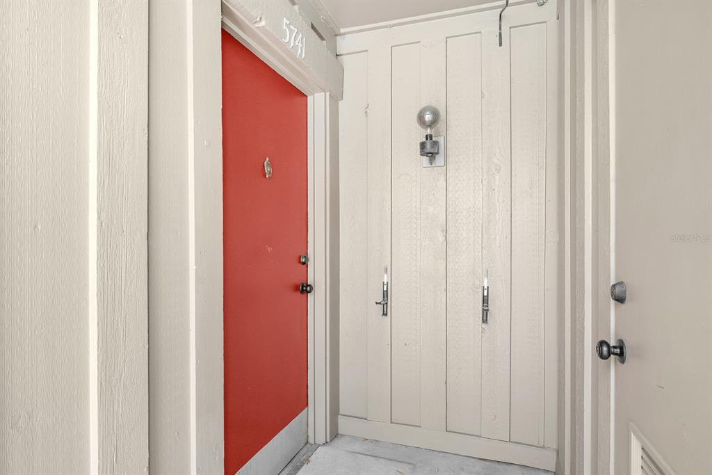 A bright red front door is positioned next to a white wooden storage closet — 5741 PEREGRINE AVENUE UNIT 28A, ORLANDO, FL