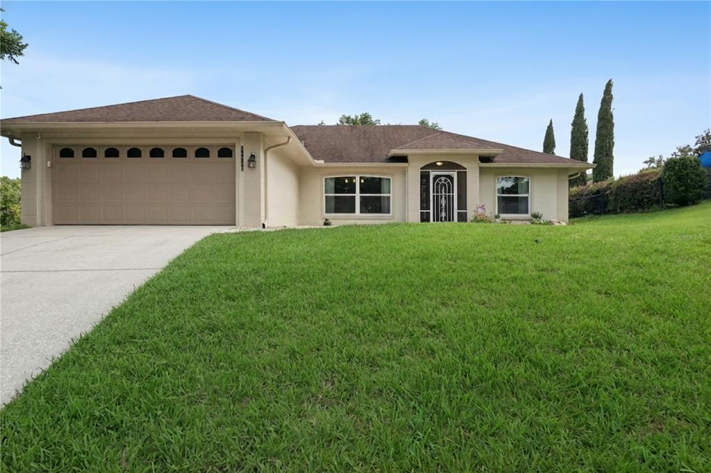 A single-story house with a tan exterior, a two-car garage, and a front lawn — 11710 GRAND BAY BLVD, CLERMONT, FL