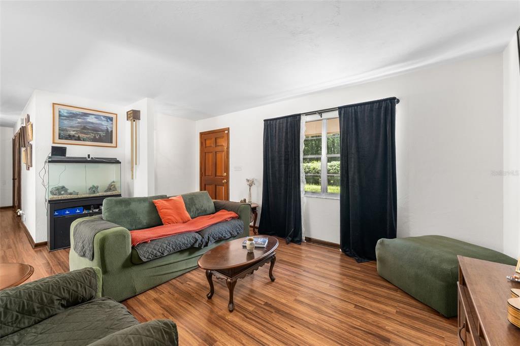 A living room features wood-look flooring, a green sofa, a coffee table, and black curtains — 22897 COUNTY ROAD 137, LAKE CITY, FL