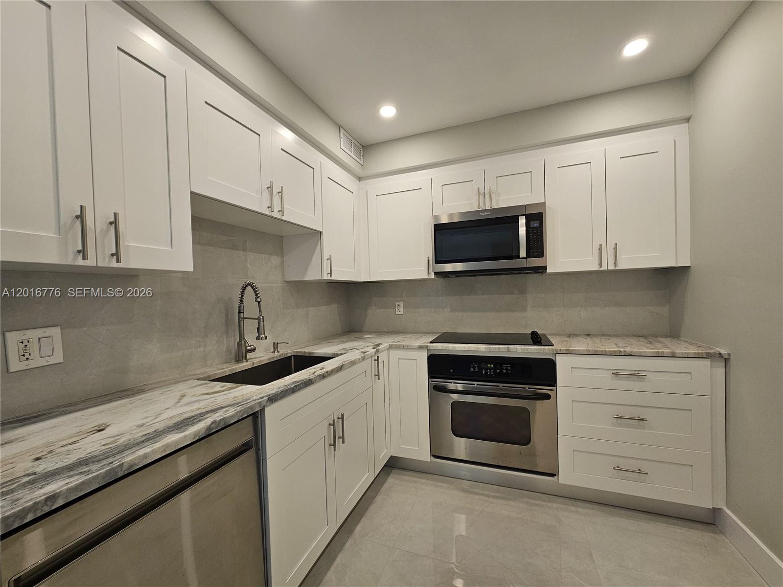 A modern kitchen features white shaker cabinets, stainless steel appliances, and marble-patterned countertops — 1985 S Ocean Dr # 2K, Hallandale Beach FL 33009, HALLANDALE BEACH, FL