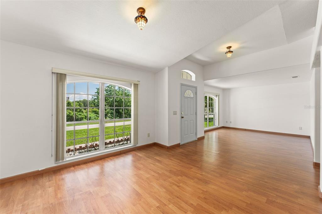 A bright living area with wood-look flooring, white walls, and a large arched window — 11603 PINELOCH LOOP, CLERMONT, FL