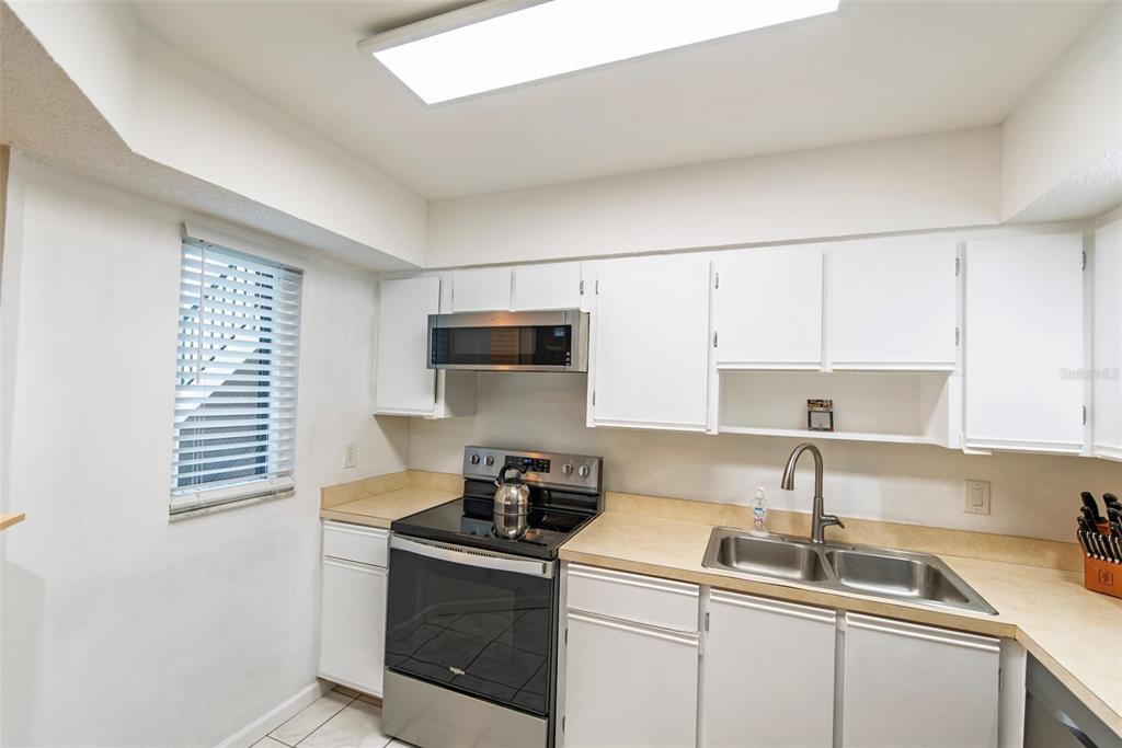 A kitchen features white cabinets, stainless steel appliances, and tan laminate countertops — 19505 QUESADA AVENUE UNIT NN101, PORT CHARLOTTE, FL