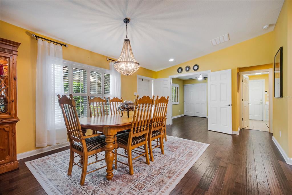 A dining room features yellow walls, a wooden table with six chairs, and dark flooring — 11951 FIORE DRIVE, ORLANDO, FL