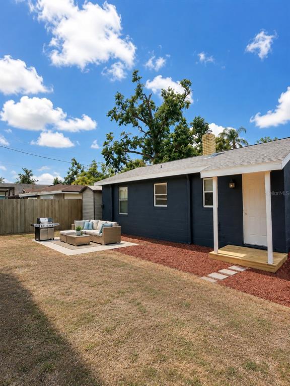 A dark-painted house exterior features a small wooden porch, a patio, and a grill — 6712 S GABRIELLE STREET, TAMPA, FL