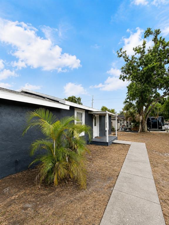 A dark-painted house exterior features a small front porch, a palm tree, and a sidewalk — 6712 S GABRIELLE STREET, TAMPA, FL