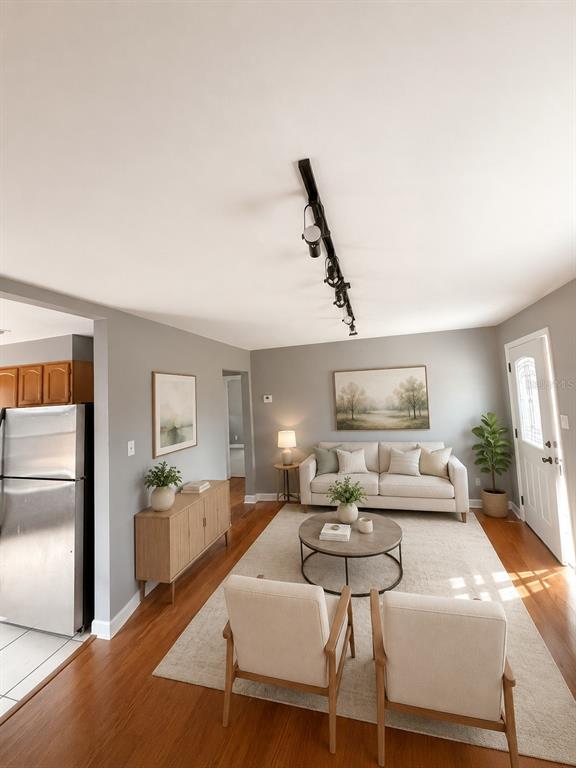 A living room features light gray walls, hardwood floors, a sofa, two armchairs, and track lighting — 6712 S GABRIELLE STREET, TAMPA, FL