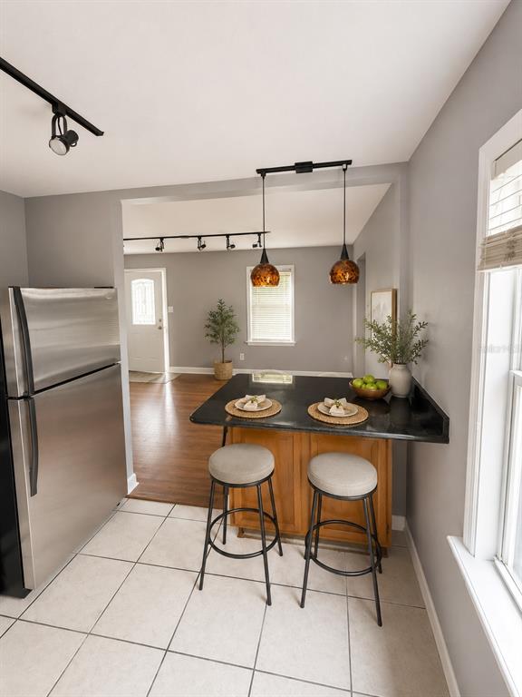 A kitchen features a black countertop island with two stools, stainless steel appliances, and tile flooring — 6712 S GABRIELLE STREET, TAMPA, FL