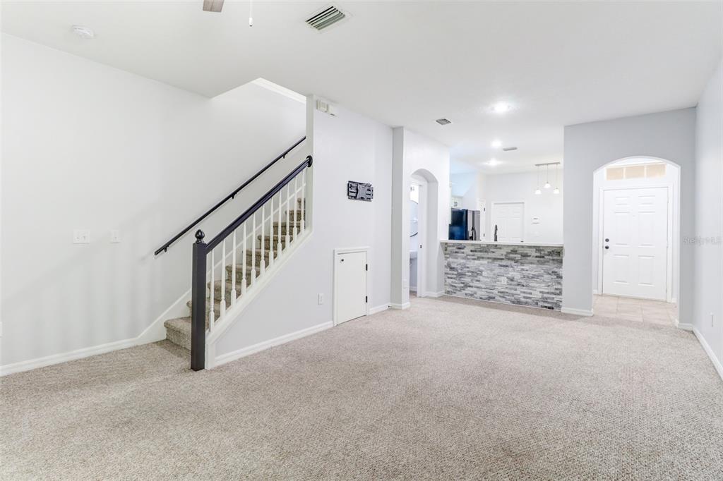 An interior view of a living area with carpeted floors, a staircase, and a breakfast bar — 6243 DUCK KEY COURT, TAMPA, FL
