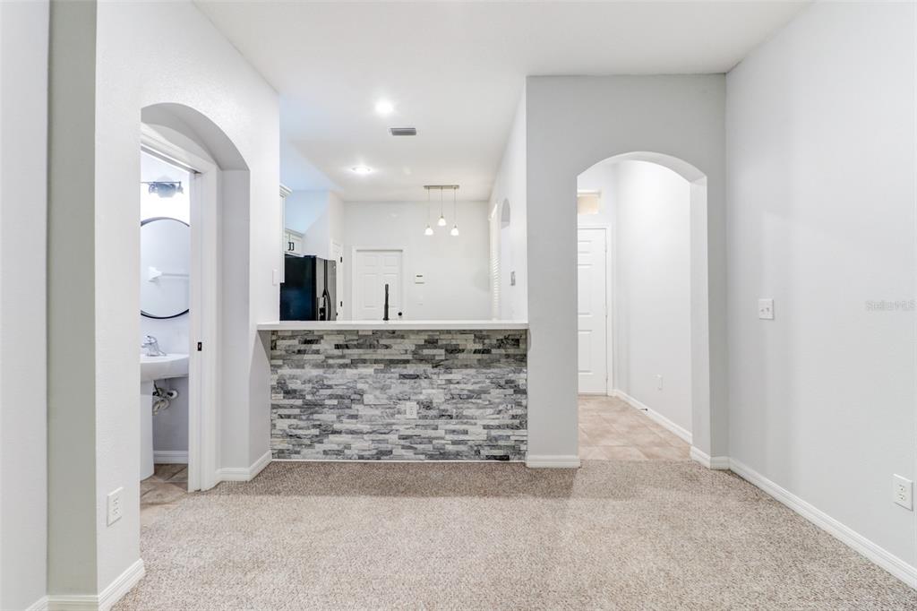 A carpeted room features a stone-faced breakfast bar, arched doorways, and a view into the kitchen — 6243 DUCK KEY COURT, TAMPA, FL