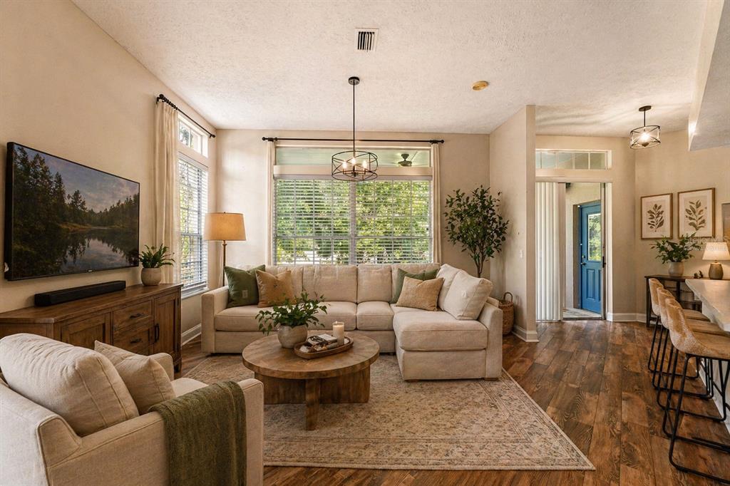A living room features a beige sectional sofa, a round wooden coffee table, and hardwood floors — 10311 PINENEEDLES DRIVE, NEW PORT RICHEY, FL