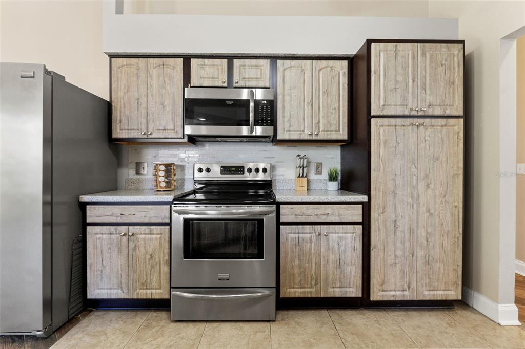 A kitchen features stainless steel appliances, light wood-grain cabinets, and speckled countertops — 10311 PINENEEDLES DRIVE, NEW PORT RICHEY, FL
