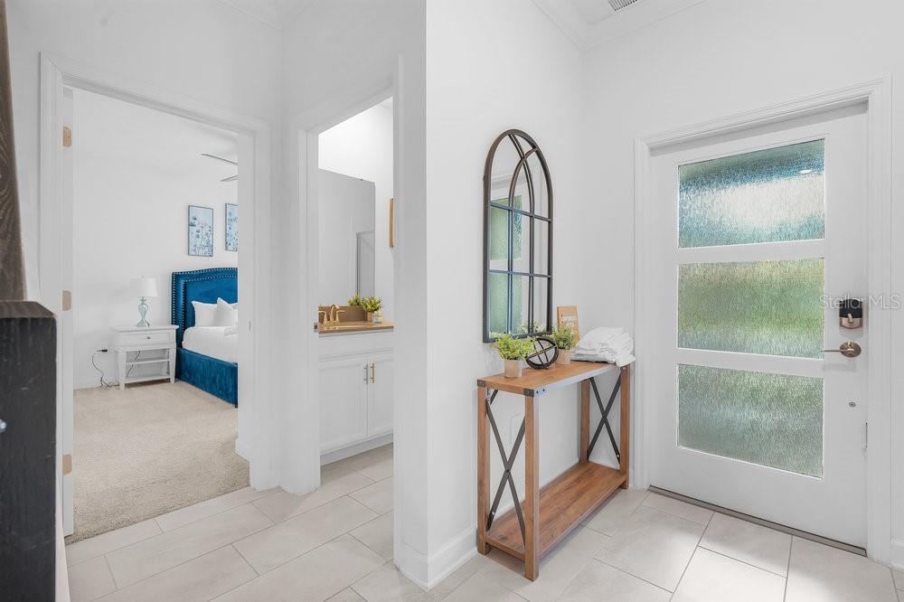 A bright entryway features a white door, a console table with a mirror, and tiled flooring — 1148 KINGSBARN STREET, DAVENPORT, FL