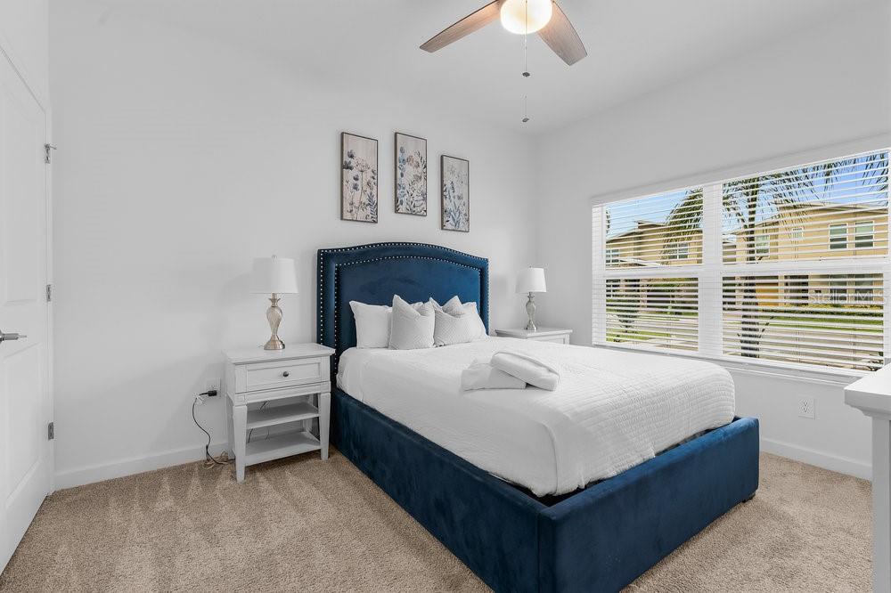 A bedroom features a blue upholstered bed, white nightstands, and three framed botanical wall prints — 1148 KINGSBARN STREET, DAVENPORT, FL