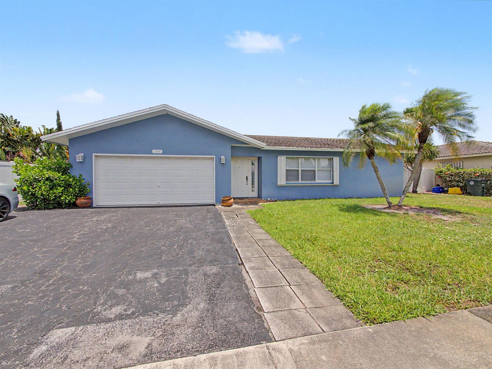 A blue single-story house with a two-car garage, a paved driveway, and two palm trees — 108 Orchard Ridge Lane, Boca Raton FL 33431, BOCA RATON, FL