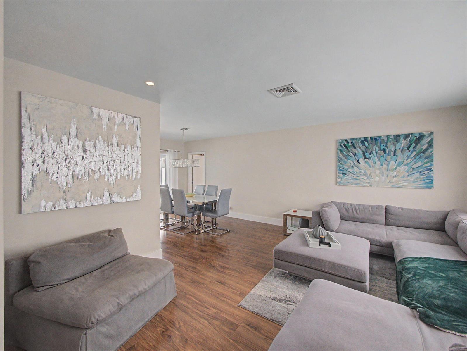 A living room with gray sectional sofas, a dining area, and two large wall paintings — 108 Orchard Ridge Lane, Boca Raton FL 33431, BOCA RATON, FL