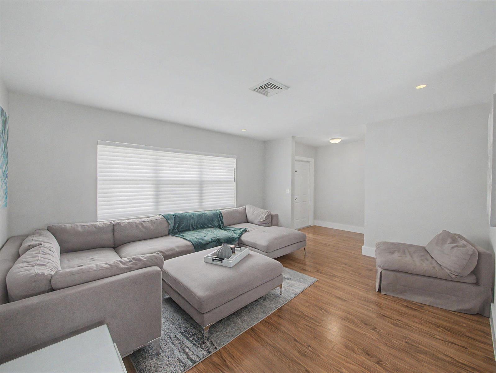 A living room features a large gray sectional sofa, matching ottoman, and wood-look flooring — 108 Orchard Ridge Lane, Boca Raton FL 33431, BOCA RATON, FL