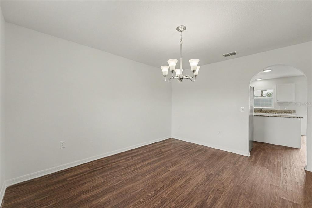 A dining area with wood-look flooring, a chandelier, and an arched entryway to the kitchen — 2007 ELMHURST LANE, MASCOTTE, FL