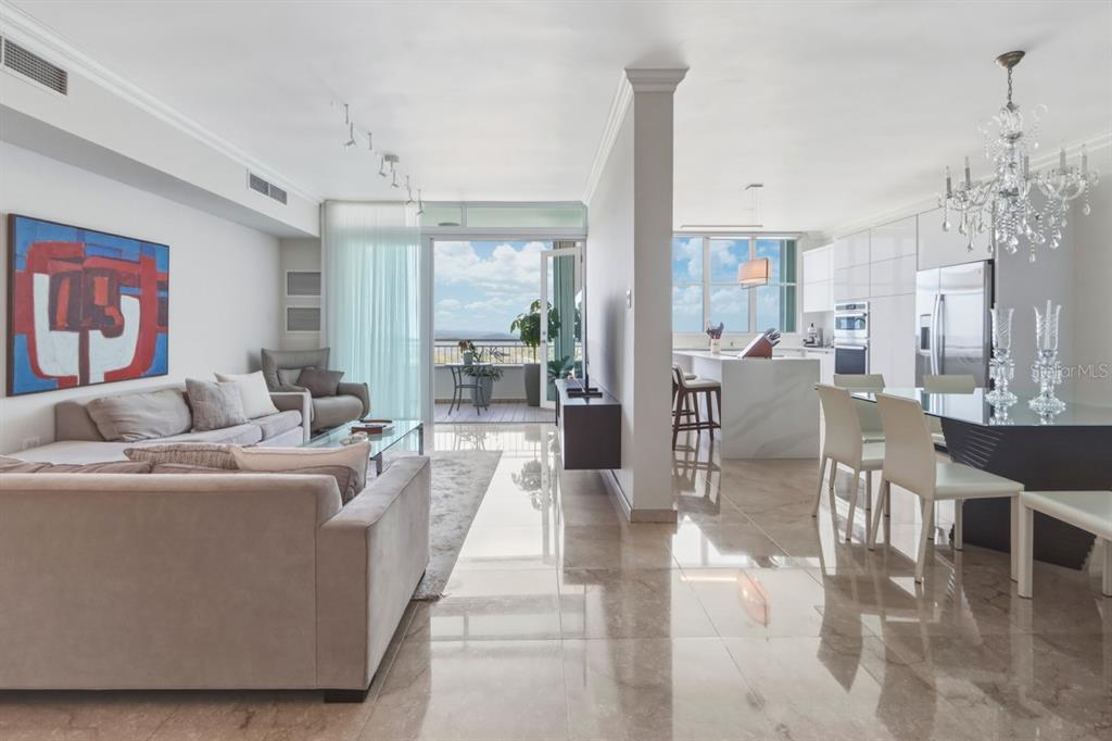 An open-concept living and dining area with marble floors, a kitchen island, and balcony access — Cond. Puerto Paseos AVENIDA FELISA RINCON GAUTIER UNIT 2104, SAN JUAN, PR
