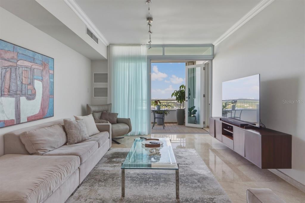 A modern living room features a beige sofa, glass coffee table, and a balcony view — Cond. Puerto Paseos AVENIDA FELISA RINCON GAUTIER UNIT 2104, SAN JUAN, PR