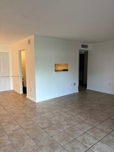 This interior view shows a room with beige tile flooring and a kitchen pass-through window — 9493 SW 76th St # L4, Miami FL 33173, MIAMI, FL