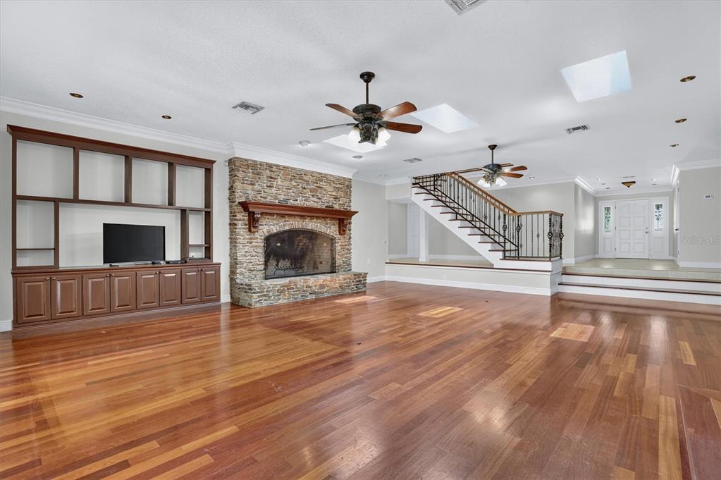 A spacious living room features hardwood floors, a stone fireplace, and a built-in media center — 306 OAK ESTATES DRIVE, ORLANDO, FL