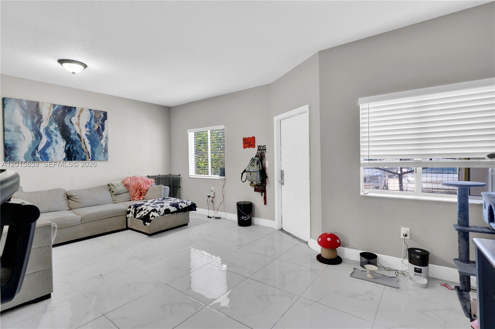 A living room features light gray walls, white tile flooring, a sectional sofa, and two windows — 1660 SE 30th St, Homestead FL 33035, HOMESTEAD, FL