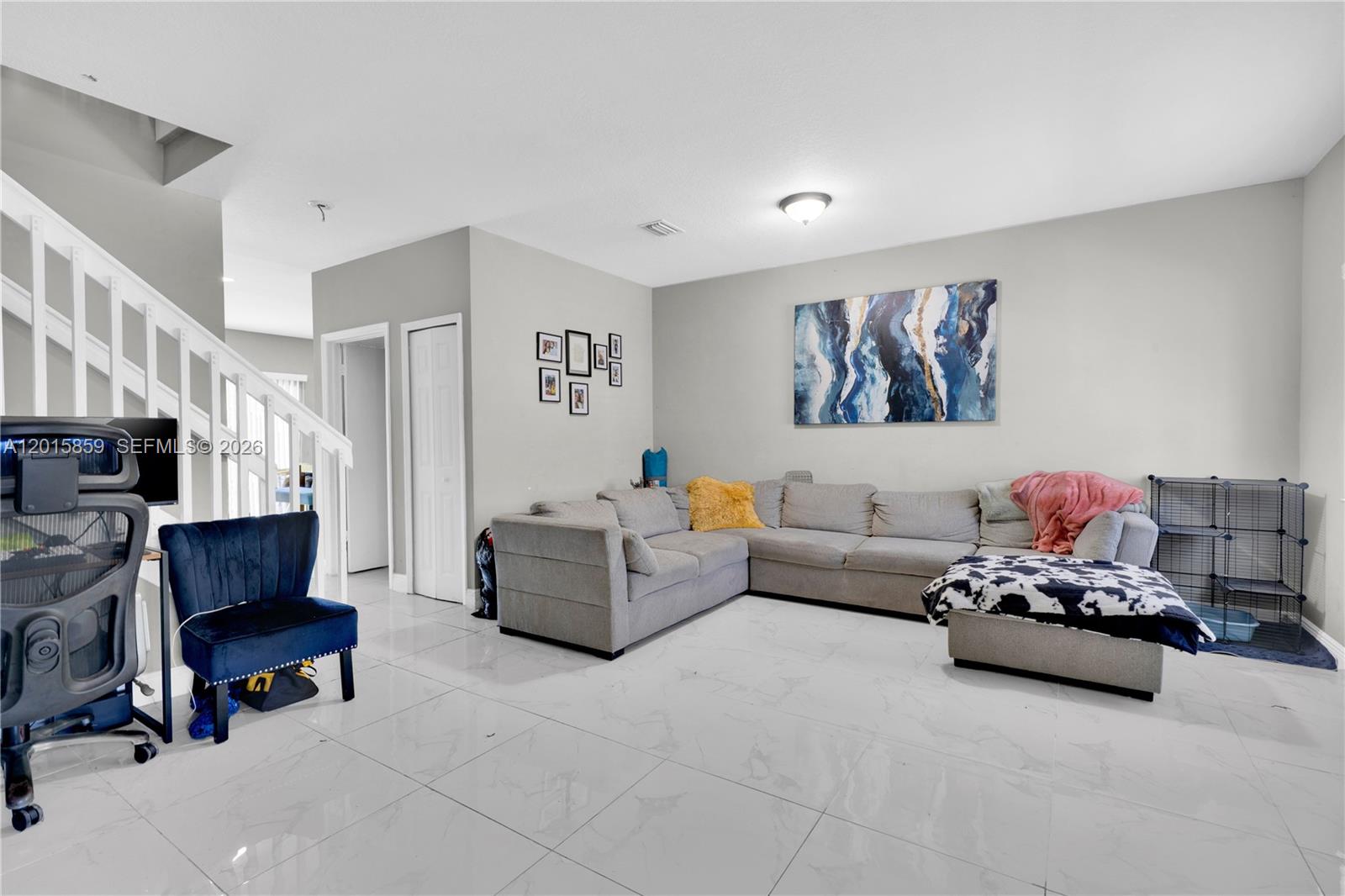 A living room features a grey sectional sofa, white tile flooring, and a staircase — 1660 SE 30th St, Homestead FL 33035, HOMESTEAD, FL