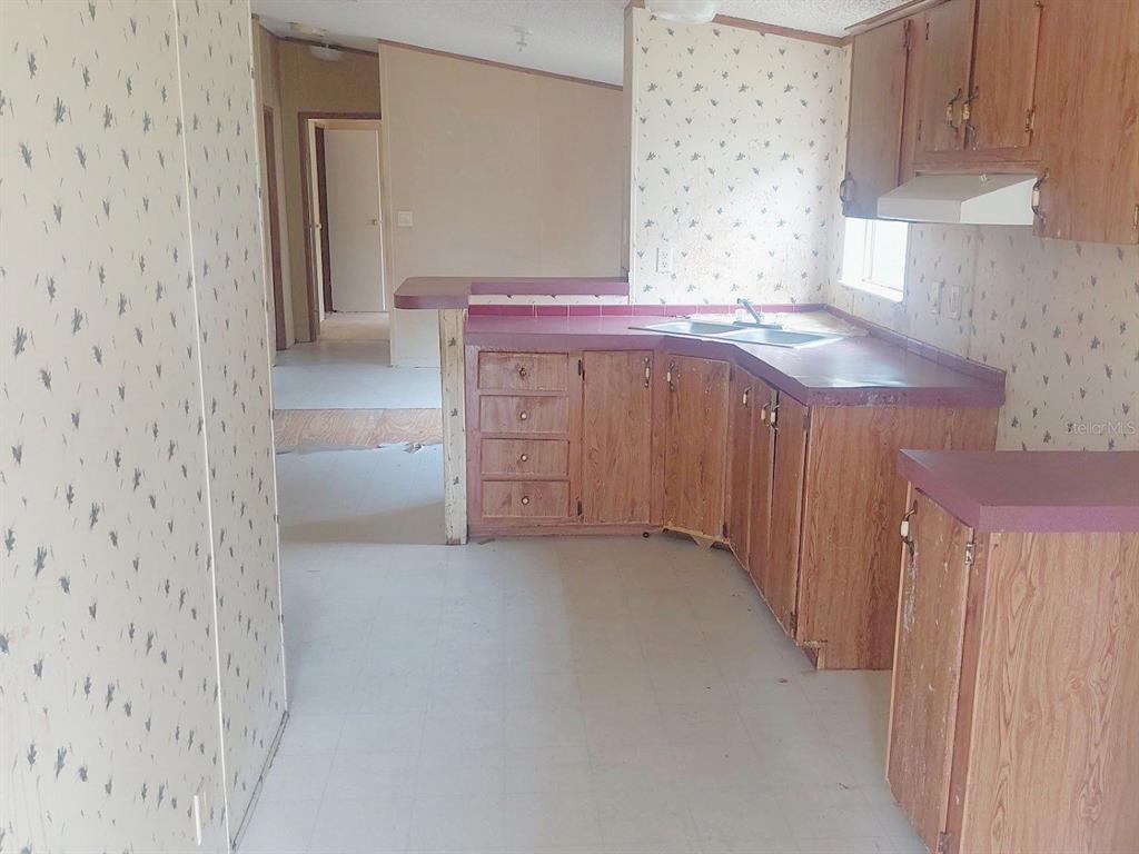 A kitchen with wood cabinets, purple laminate countertops, and patterned wallpaper — 1289 SW BEDENBAUGH LANE, LAKE CITY, FL