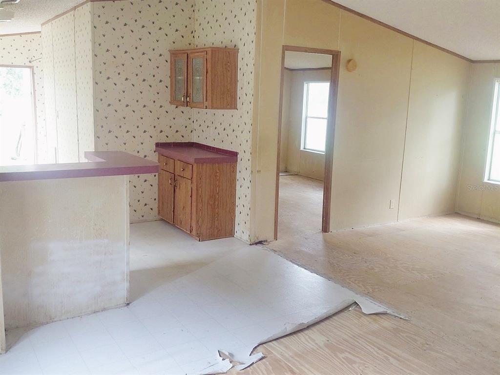 An interior view shows a kitchen with wood cabinets and a living area with flooring — 1289 SW BEDENBAUGH LANE, LAKE CITY, FL
