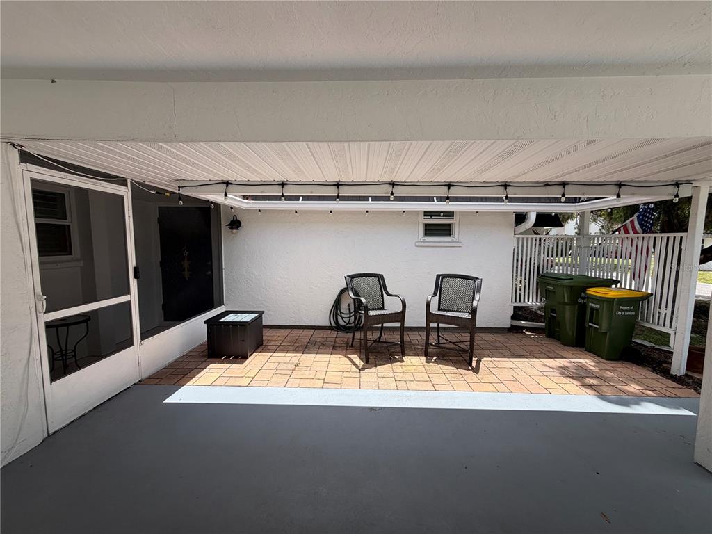 A single-story home features a concrete driveway, a covered carport, and a large shade tree — 3935 PANOLA LANE UNIT 183, SARASOTA, FL