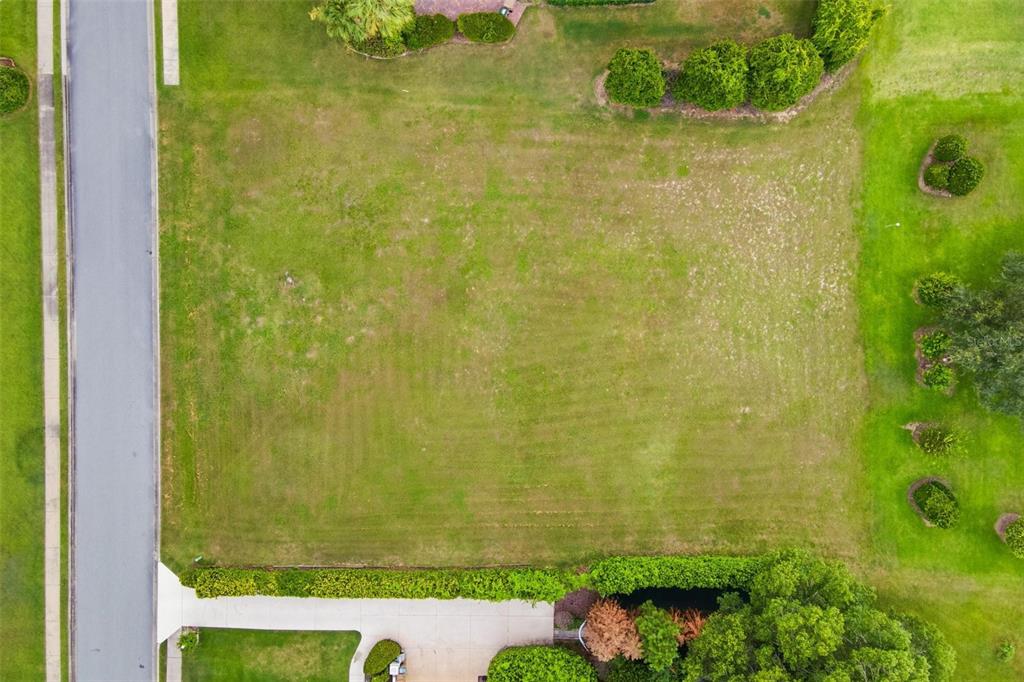 An aerial view shows a vacant residential lot surrounded by houses and green lawns — TACOMA DRIVE, LADY LAKE, FL