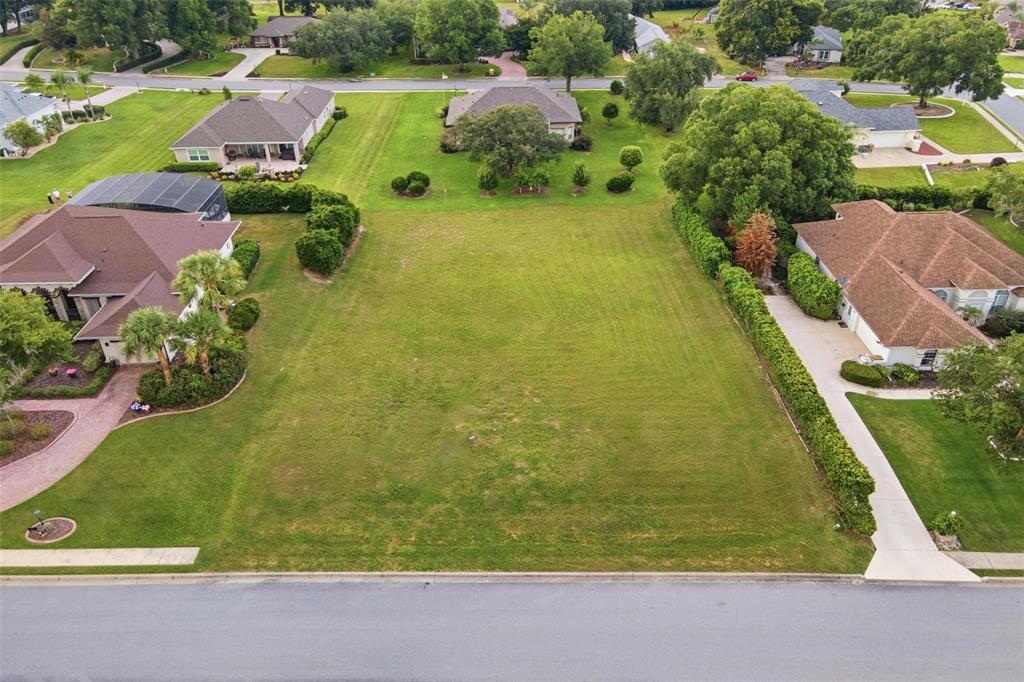 An aerial view shows a rectangular, grassy vacant lot bordered by a road and landscaping — TACOMA DRIVE, LADY LAKE, FL