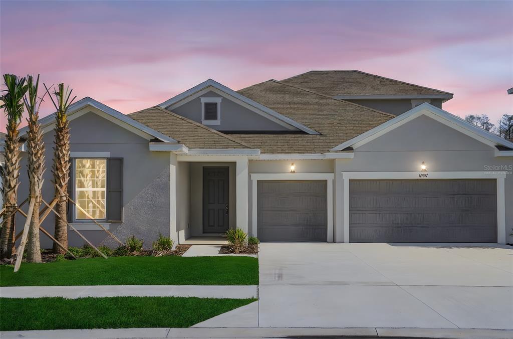 A single-story house with a gray exterior, two garage doors, and a front entrance — 17527 VALLEYWOOD PARKWAY, LAND O LAKES, FL