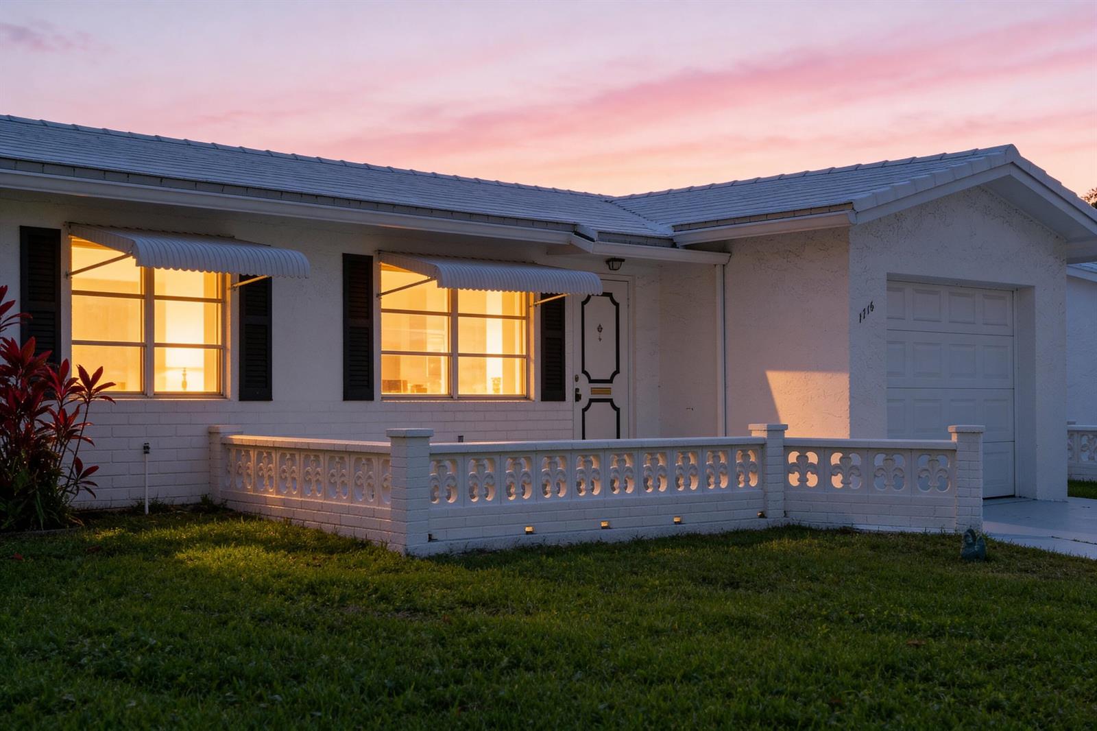 A white house with a decorative concrete block wall and illuminated windows at sunset — 1714 SW 19th Drive, Boynton Beach FL 33426, BOYNTON BEACH, FL
