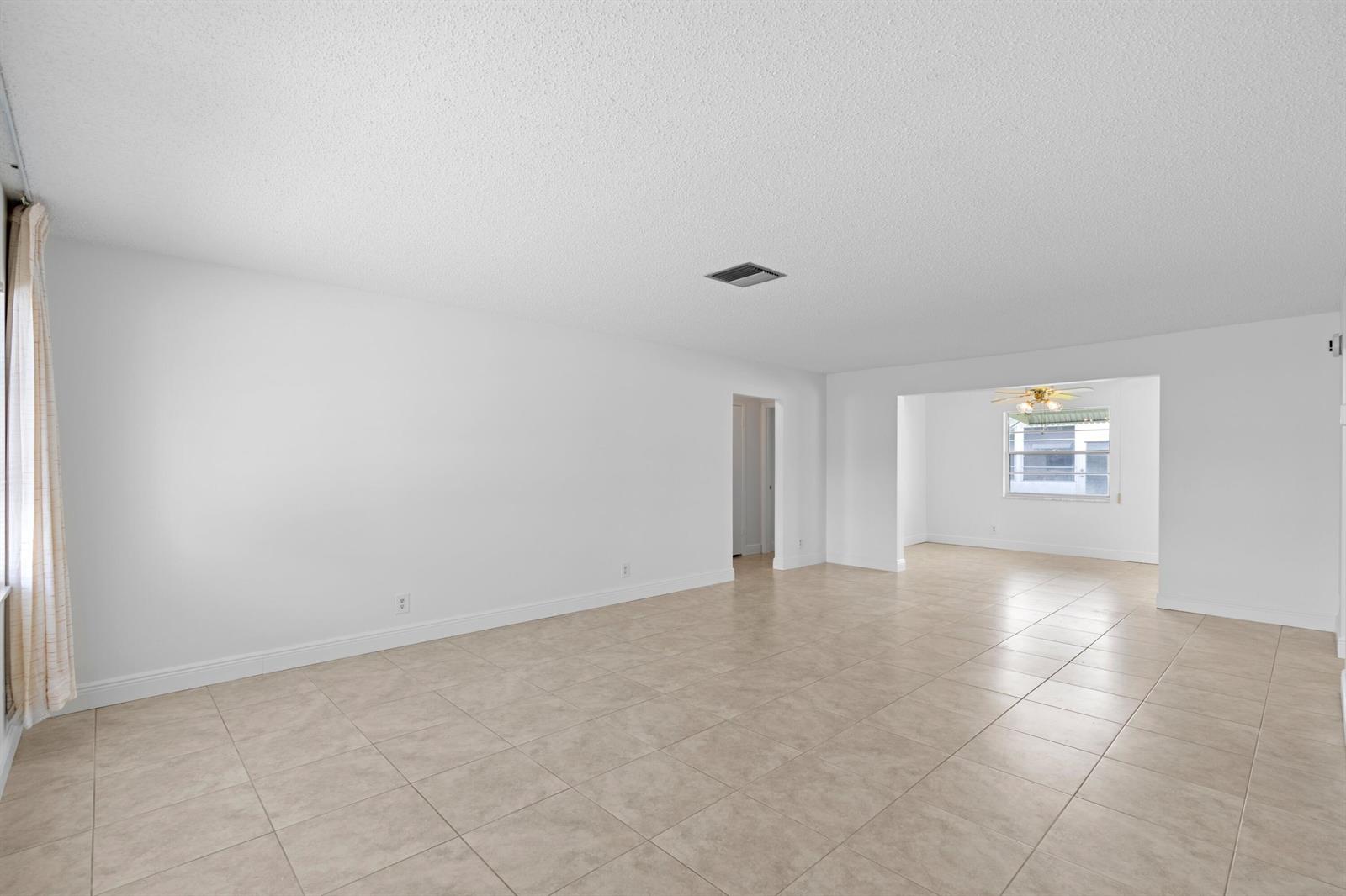 An empty living room with white walls, beige tile flooring, and a ceiling fan — 1714 SW 19th Drive, Boynton Beach FL 33426, BOYNTON BEACH, FL