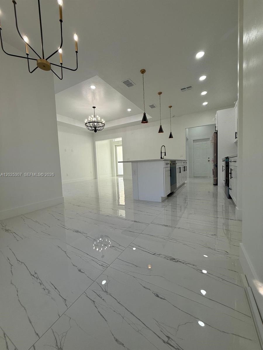 A modern kitchen features a white island, pendant lighting, and polished marble-look tile flooring — 4007 E 13 ST, Lehigh Acres FL 33972, LEHIGH ACRES, FL