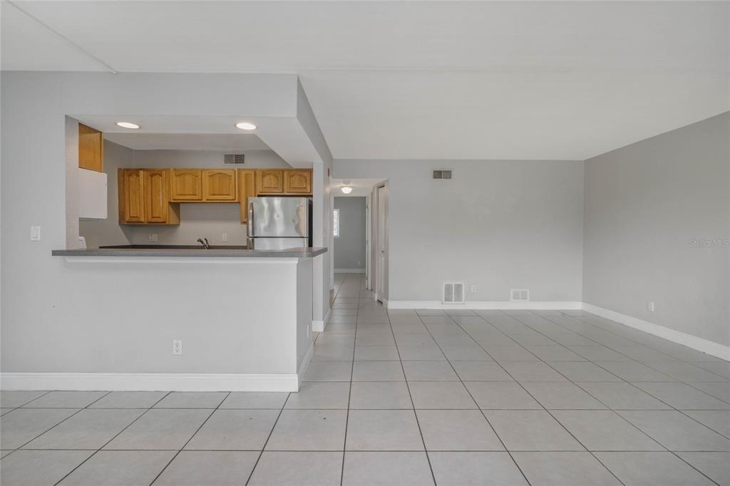 An open-concept living area features light gray walls, tiled floors, and a kitchen with wood cabinets — 900 S PENINSULA DRIVE UNIT 207, DAYTONA BEACH, FL
