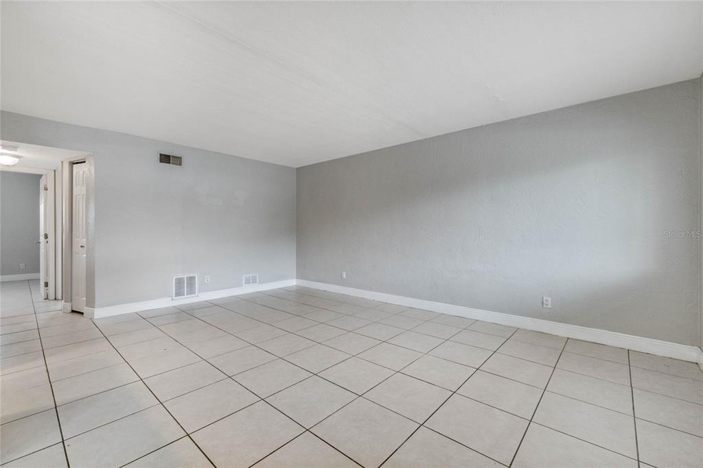 An empty room features light gray walls, white baseboards, and large square floor tiles — 900 S PENINSULA DRIVE UNIT 207, DAYTONA BEACH, FL