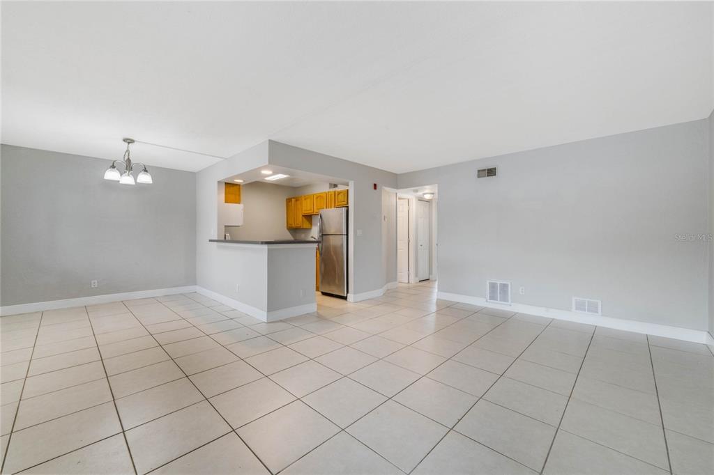 A tiled living area features an open kitchen with wooden cabinets and stainless steel appliances — 900 S PENINSULA DRIVE UNIT 207, DAYTONA BEACH, FL