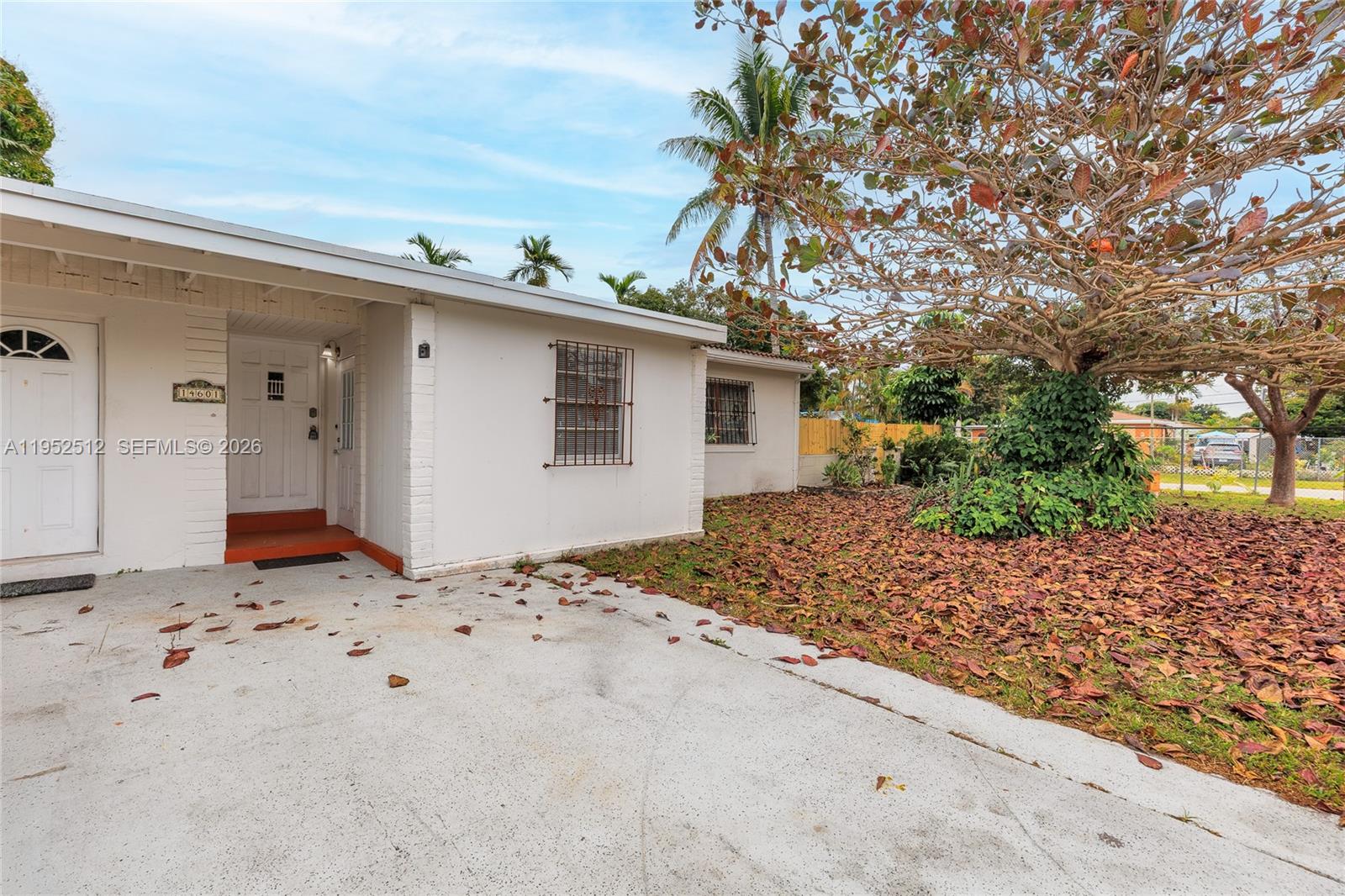 A white single-story house exterior features a concrete driveway and a large tree — 14601 NW 10th Ave, Miami FL 33168, MIAMI, FL