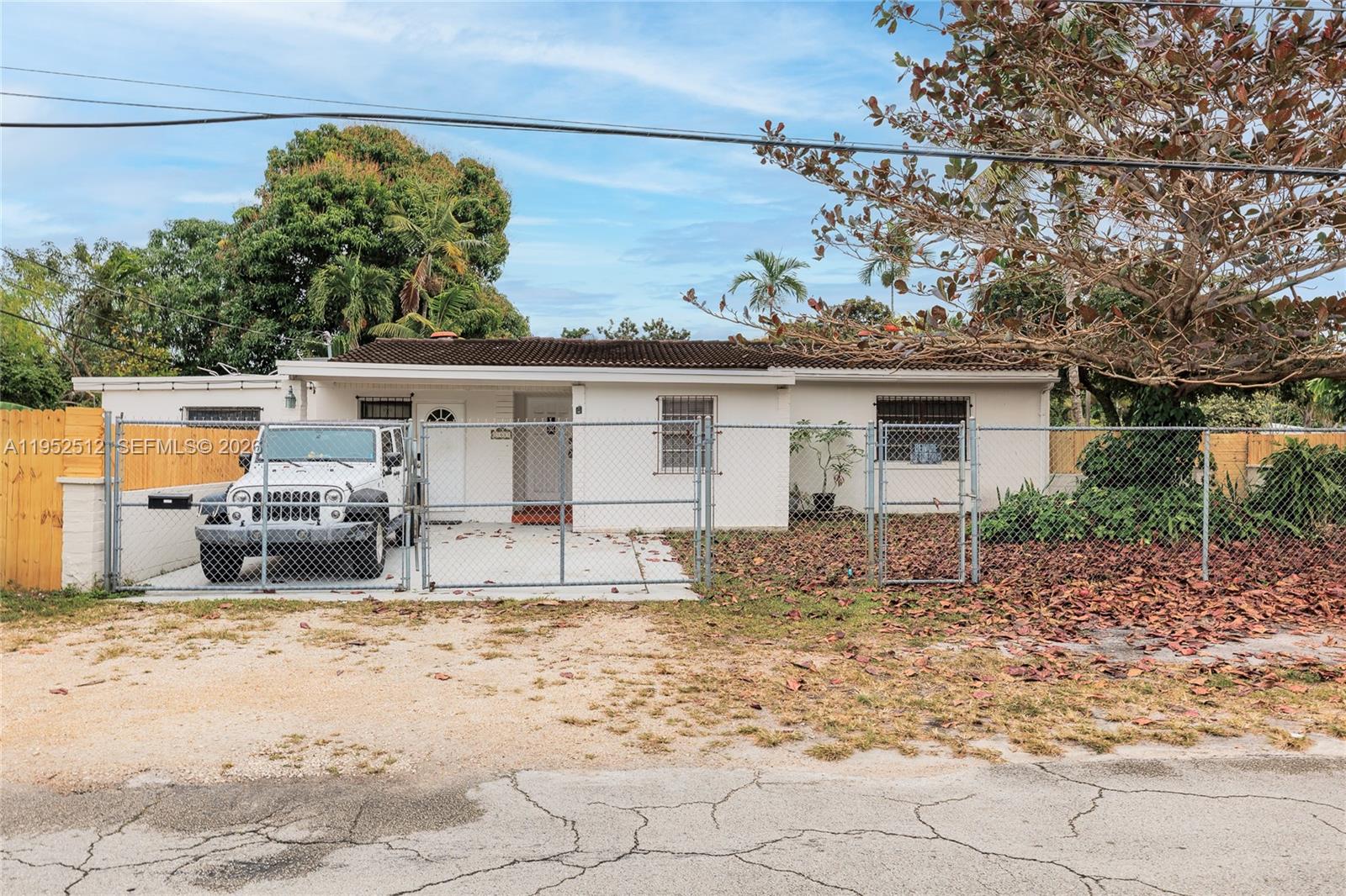 A single-story white house with a chain-link fence and a parked white Jeep — 14601 NW 10th Ave, Miami FL 33168, MIAMI, FL