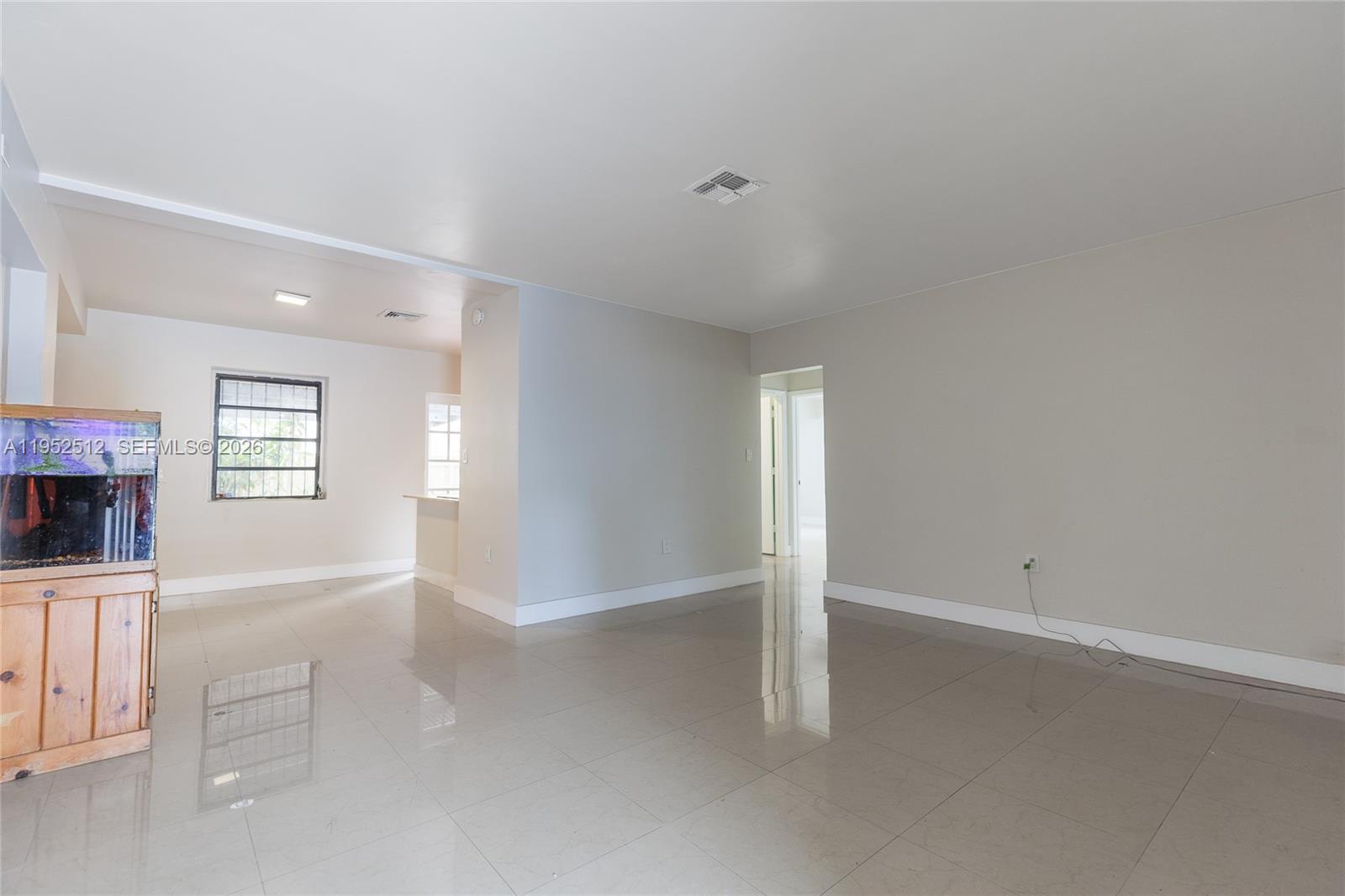 An empty room with light-colored tile flooring, beige walls, and a fish tank — 14601 NW 10th Ave, Miami FL 33168, MIAMI, FL