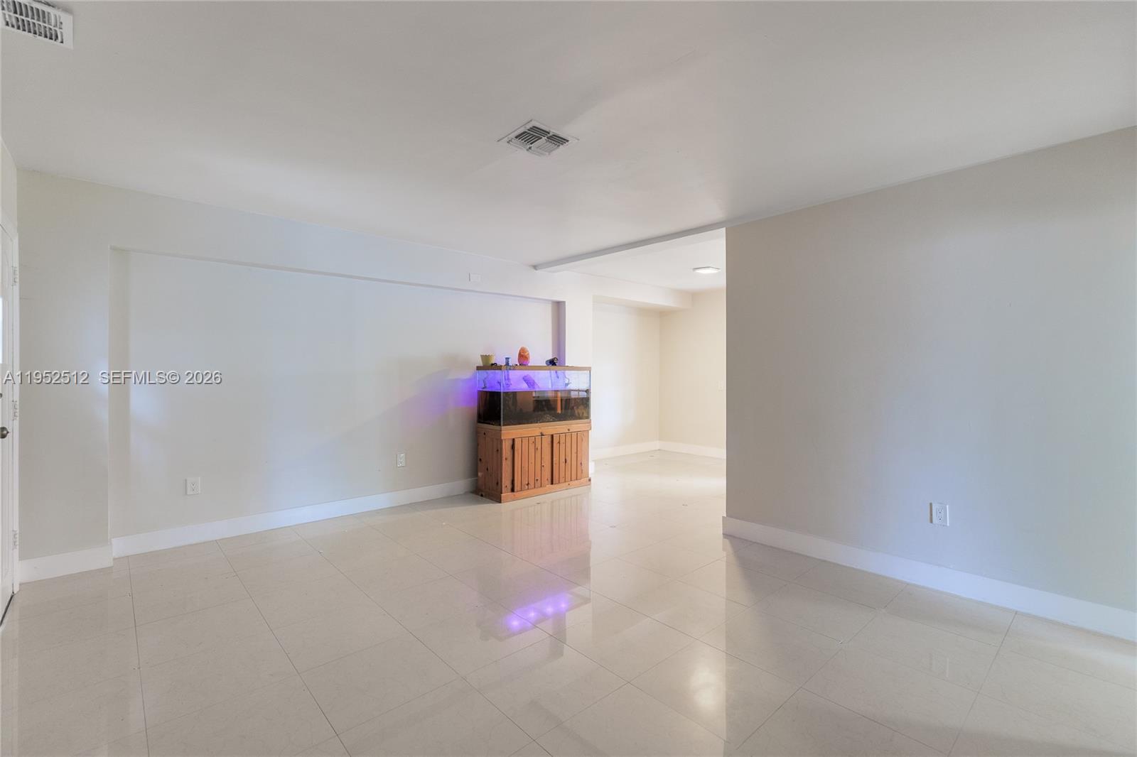 A bright, empty room features light-colored tile flooring, plain walls, and a large fish tank — 14601 NW 10th Ave, Miami FL 33168, MIAMI, FL